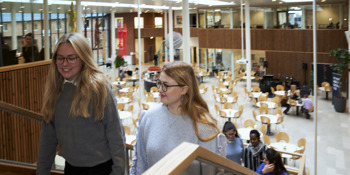 En flok elever kommender gående op ad en trappe i et fællesområde på social- og sundhedsskolen. De forreste to elever smiler let og kigger væk fra kameraet.